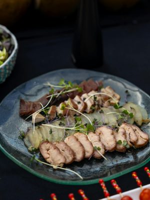 Plate with assorted smoked meats and microgreens, perfect for gourmet dining.